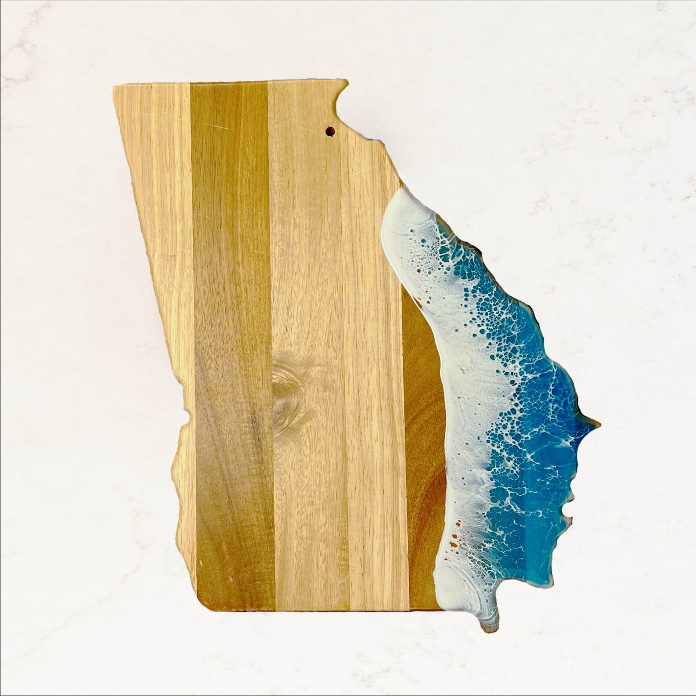 Wooden cutting board with a resin-embedded wave design on a white background