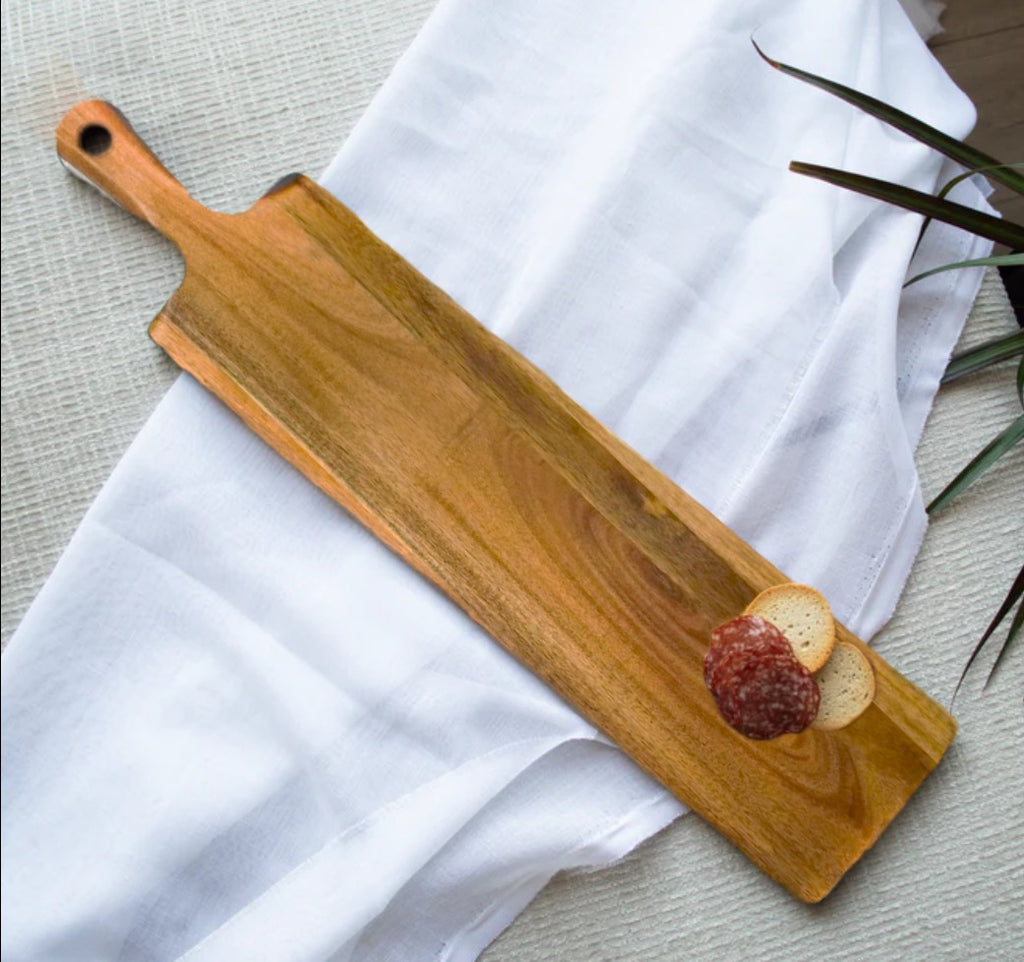 Wooden serving board with a white cloth and a plant in the background