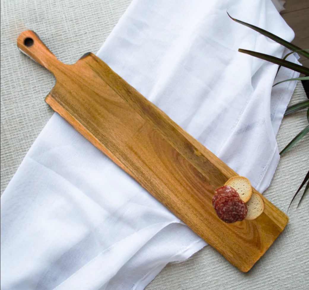 Wooden serving board with a white cloth and a plant in the background