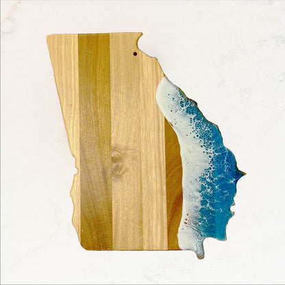 Wooden cutting board with a resin-embedded wave design on a white background